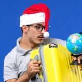 front close view young male holding globe yellow bag blue wall plane vacation trip