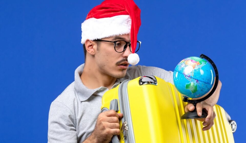 5 نصائح لتجنب اكتئاب مواسم الإجازات front close view young male holding globe yellow bag blue wall plane vacation trip
